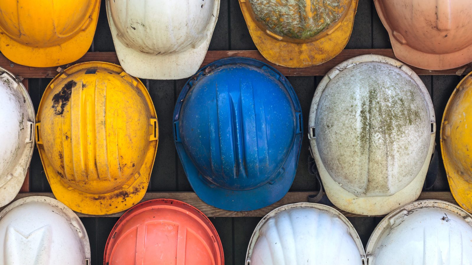 Various worn hard hats laid out on a surface.